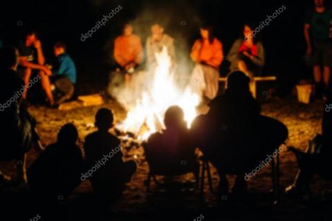 люди сидят в ночное время вокруг костра. Фото:  depositphotos com/